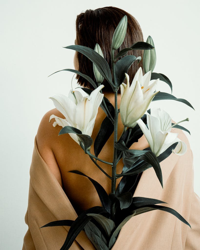 A tasteful display of a woman with a bouquet of lilies against a neutral backdrop.