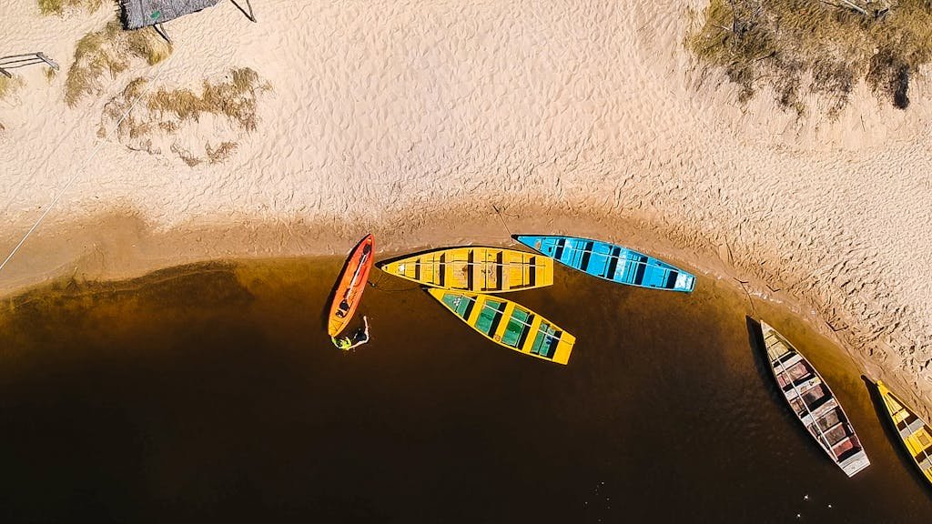 Aerial shot of vibrant boats on a sandy beach in Baía Formosa, Brazil.