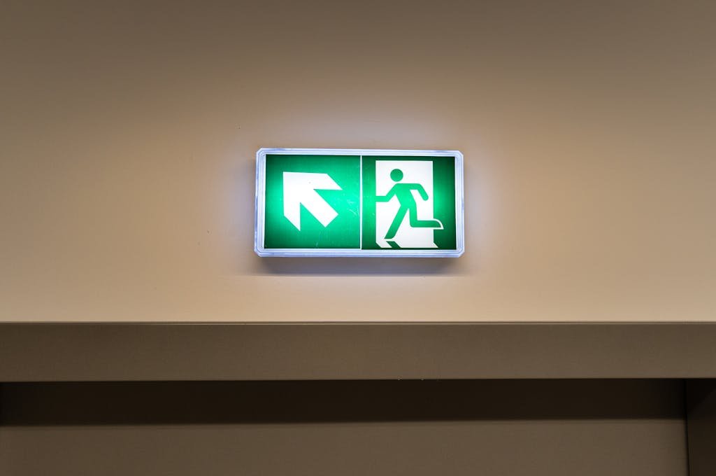 clicker up emergency exit sign with arrow symbol in indoor hallway, indicating direction to safety.