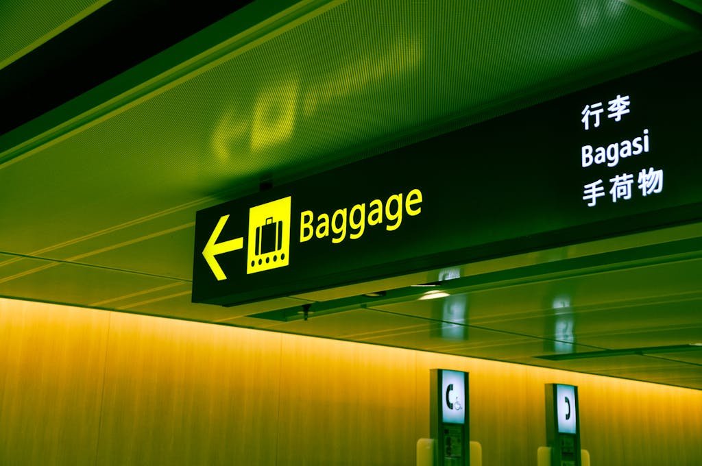 Illuminated airport baggage sign with multilingual translations clickup direction for travelers.