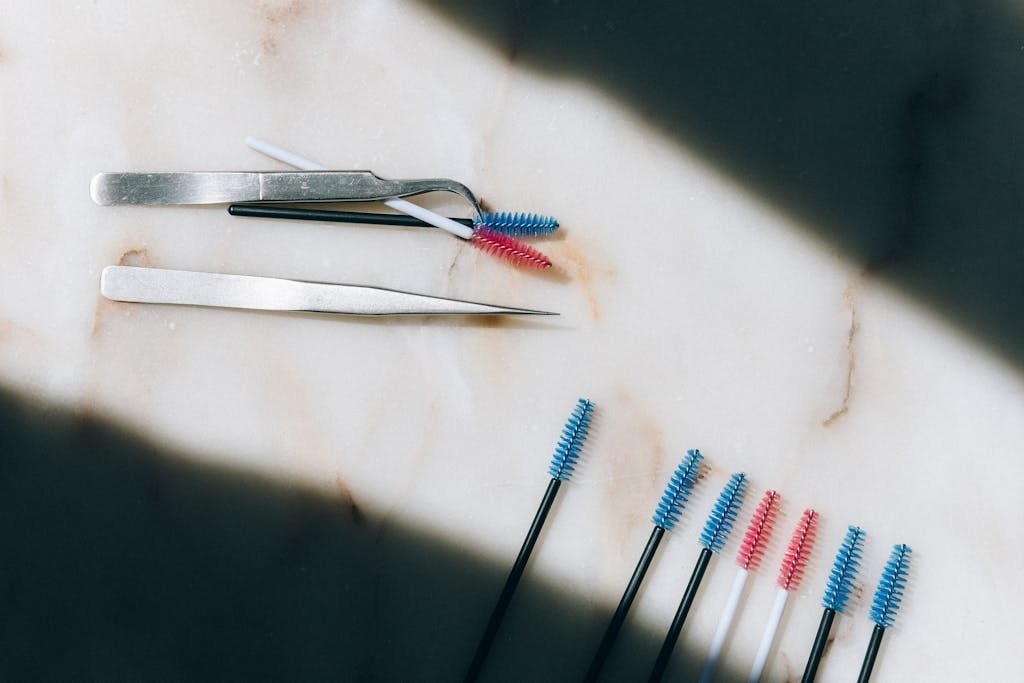 Colorful eyelash brushes and tweezers on a marble surface. Perfect for beauty and cosmetic themes.