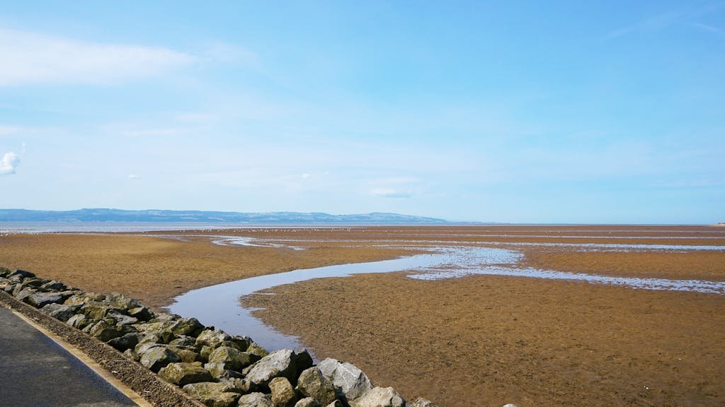 Kirby view of tidal flats in West Kirby, England, under a blue sky, highlighting coastal landscape.