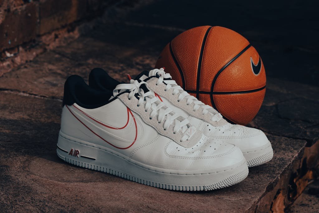 Stylish white sneakers paired with a Nike basketball on a rustic stone background.