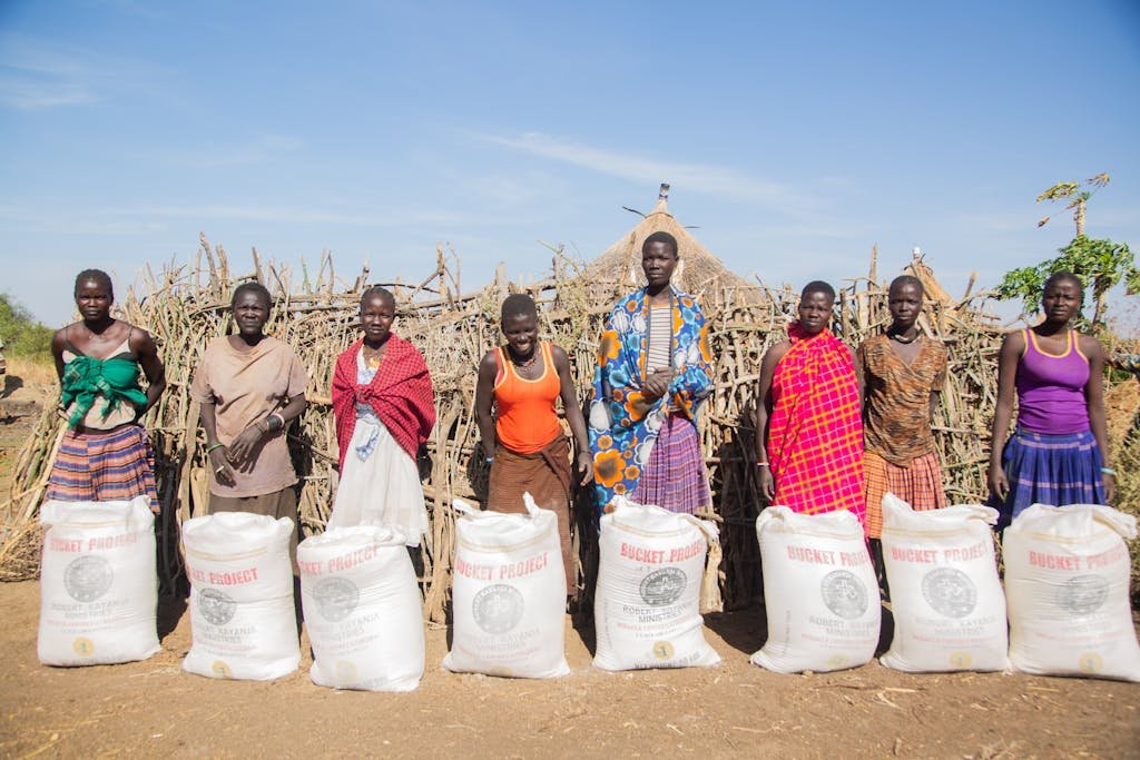 urakata de support shiteta of African individuals stand proudly with donated food bags outside.