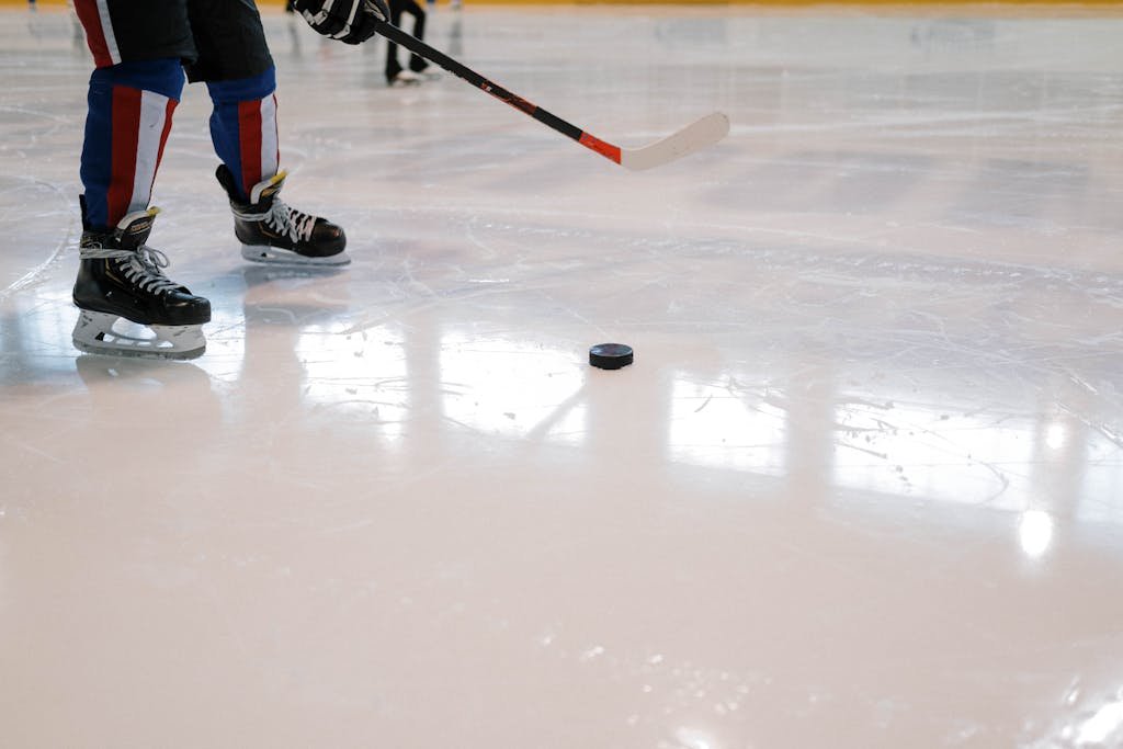 Manual Settings HSSGameStick of a hockey player maneuvering with stick and puck on ice rink.