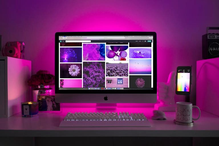 Modern desk setup with neon lighting and a desktop computer displaying colorful images. Official Websites