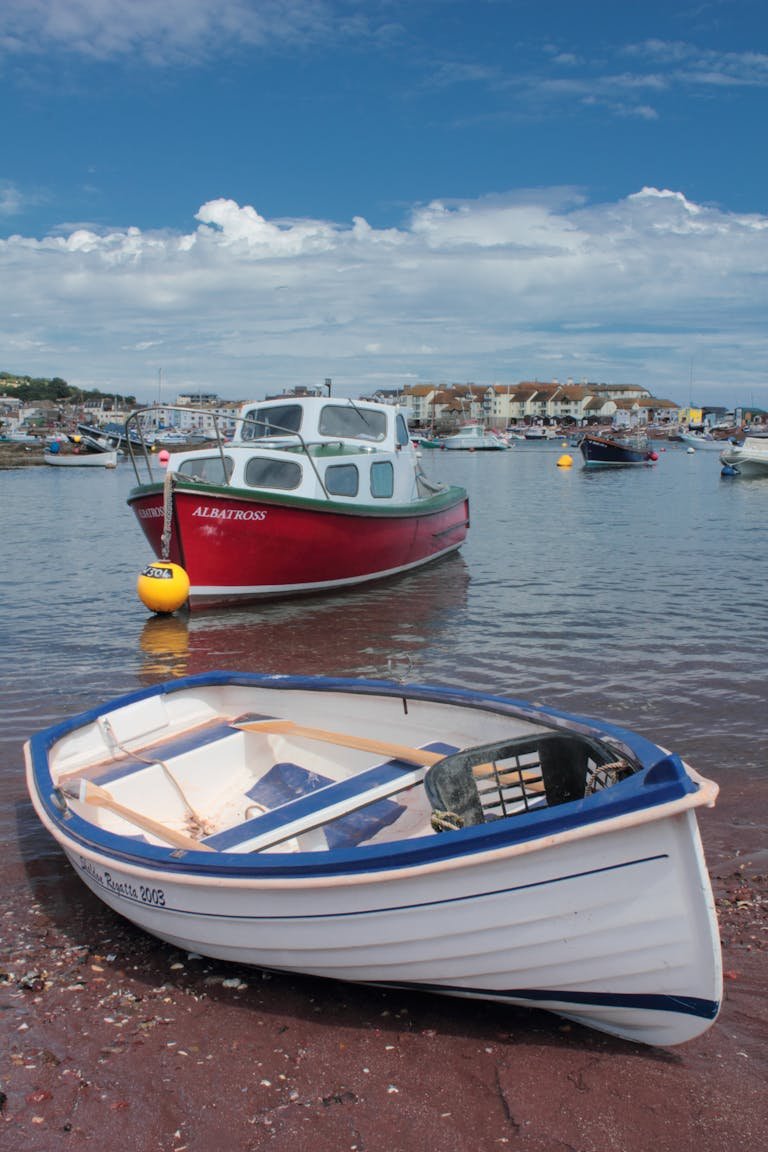 Vibrant fishing and Veneajelu anchored in a scenic harbor under clear skies.