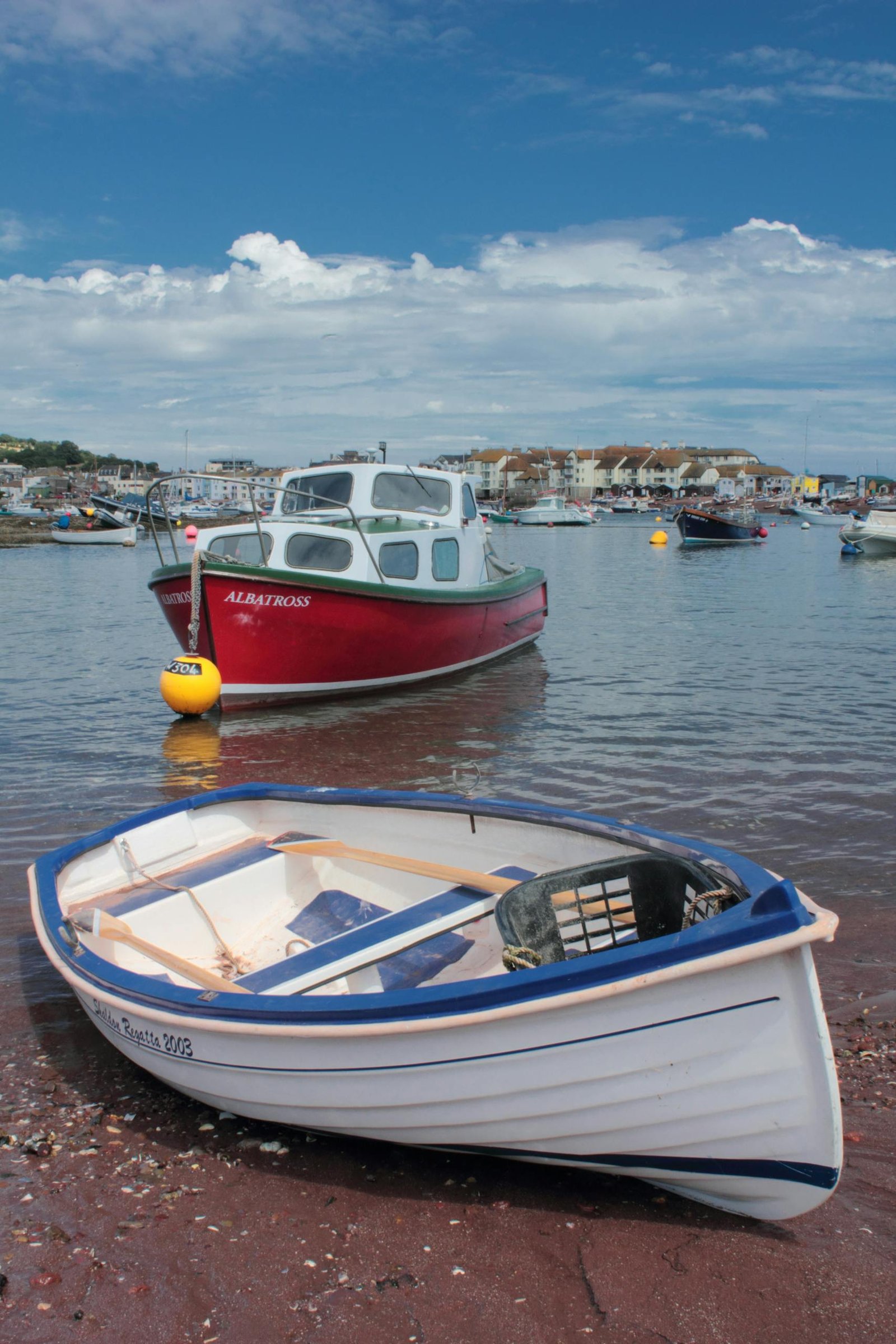 Vibrant fishing and Veneajelu anchored in a scenic harbor under clear skies.