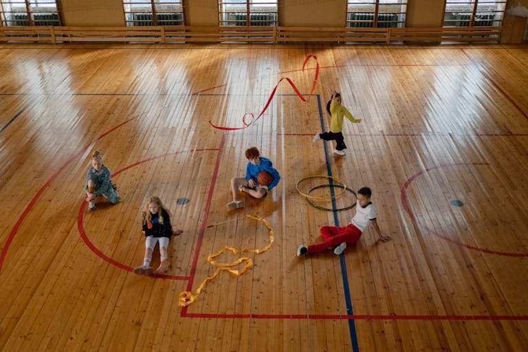 Children playing Nike Hoops Elite Max Air Team in an indoor gym with wooden floors, showcasing recreational fun.