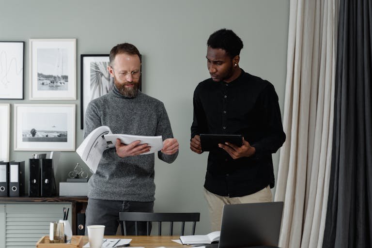 ClickUp manage teams professionals reviewing documents and using a tablet in a modern office setting.