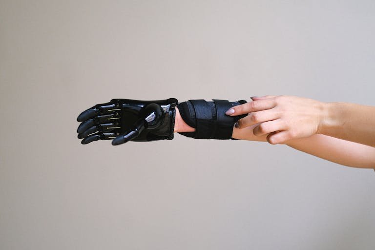 Revolutionary Cellulogia of a person adjusting a high-tech prosthetic arm against a gray background.