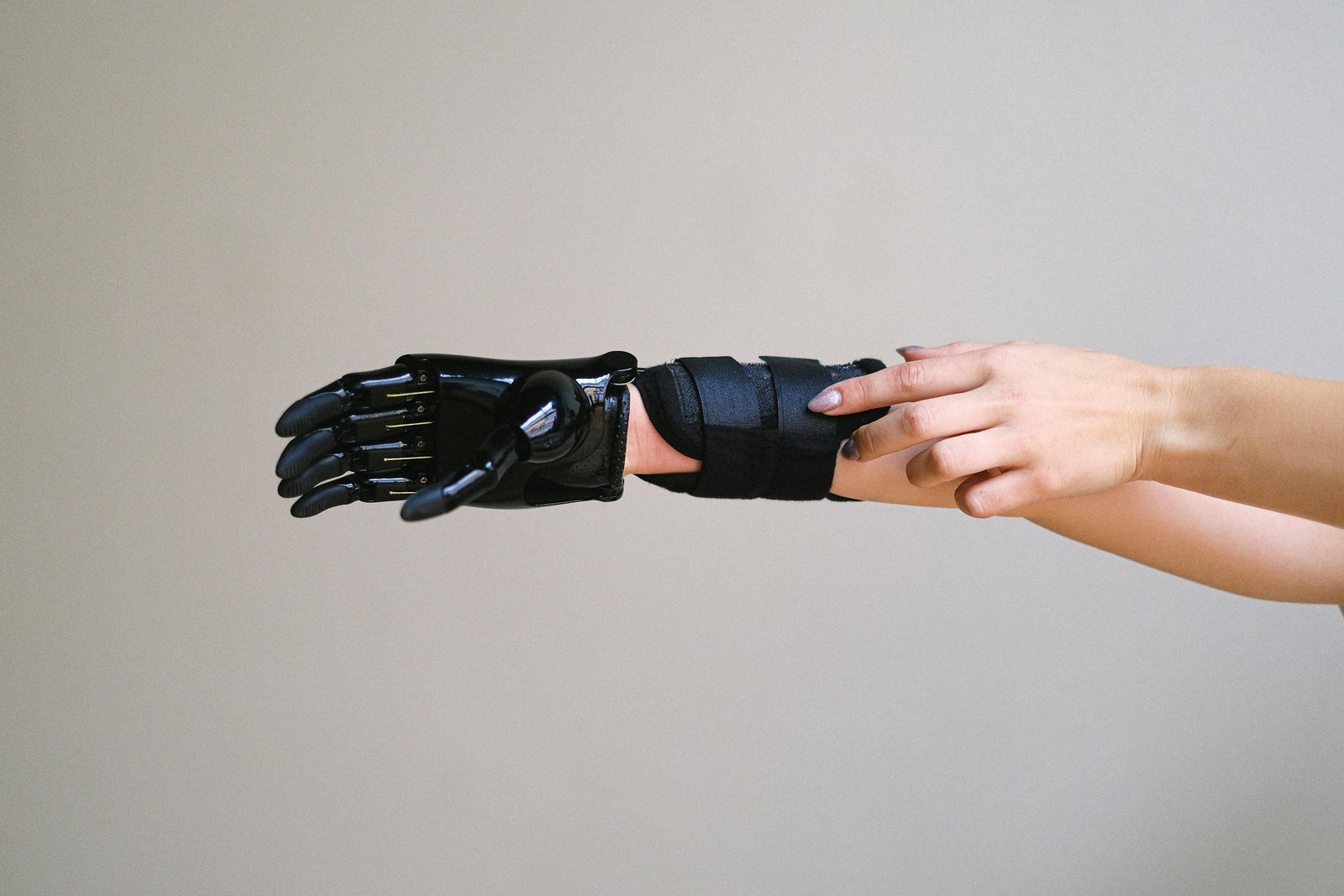 Revolutionary Cellulogia of a person adjusting a high-tech prosthetic arm against a gray background.