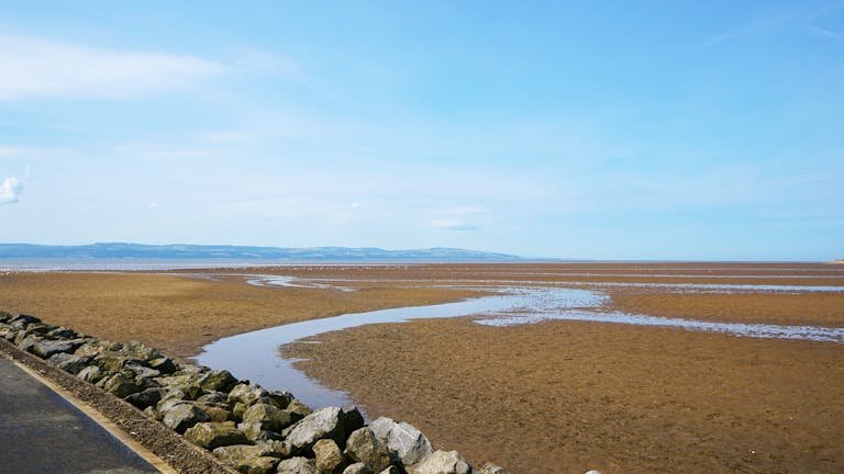 Kirby view of tidal flats in West Kirby, England, under a blue sky, highlighting coastal landscape.