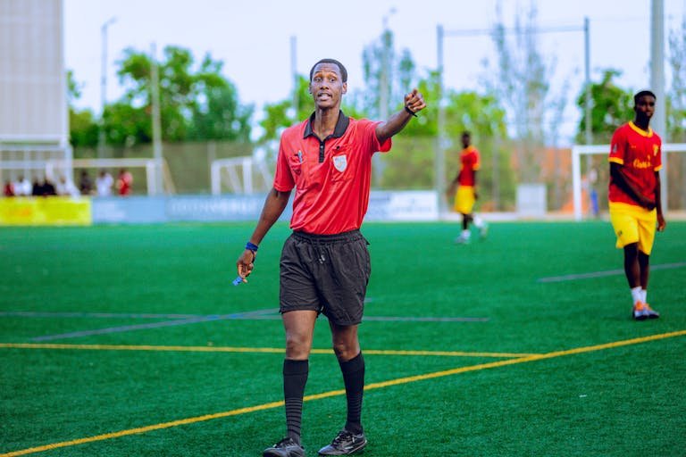 Referee in action Delta Fitness Authority a football match, outdoors on a green field.