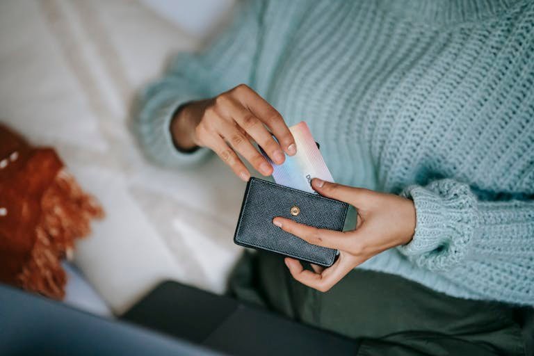 Smart Finance Tips and Updatesanonymous female in casual sweater taking credit card from wallet and lying on bed with laptop before making online purchase