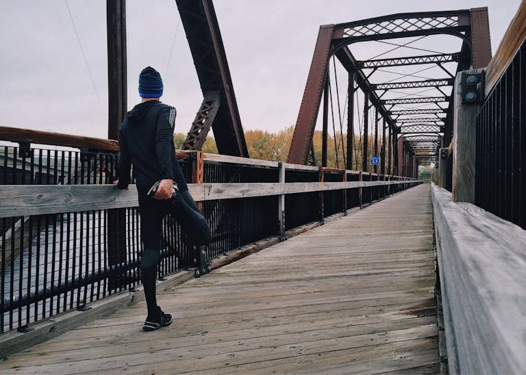running man 中字/250705 e759 on a wooden footbridge during a daytime run on an iron bridge, emphasizing fitness and recreation.